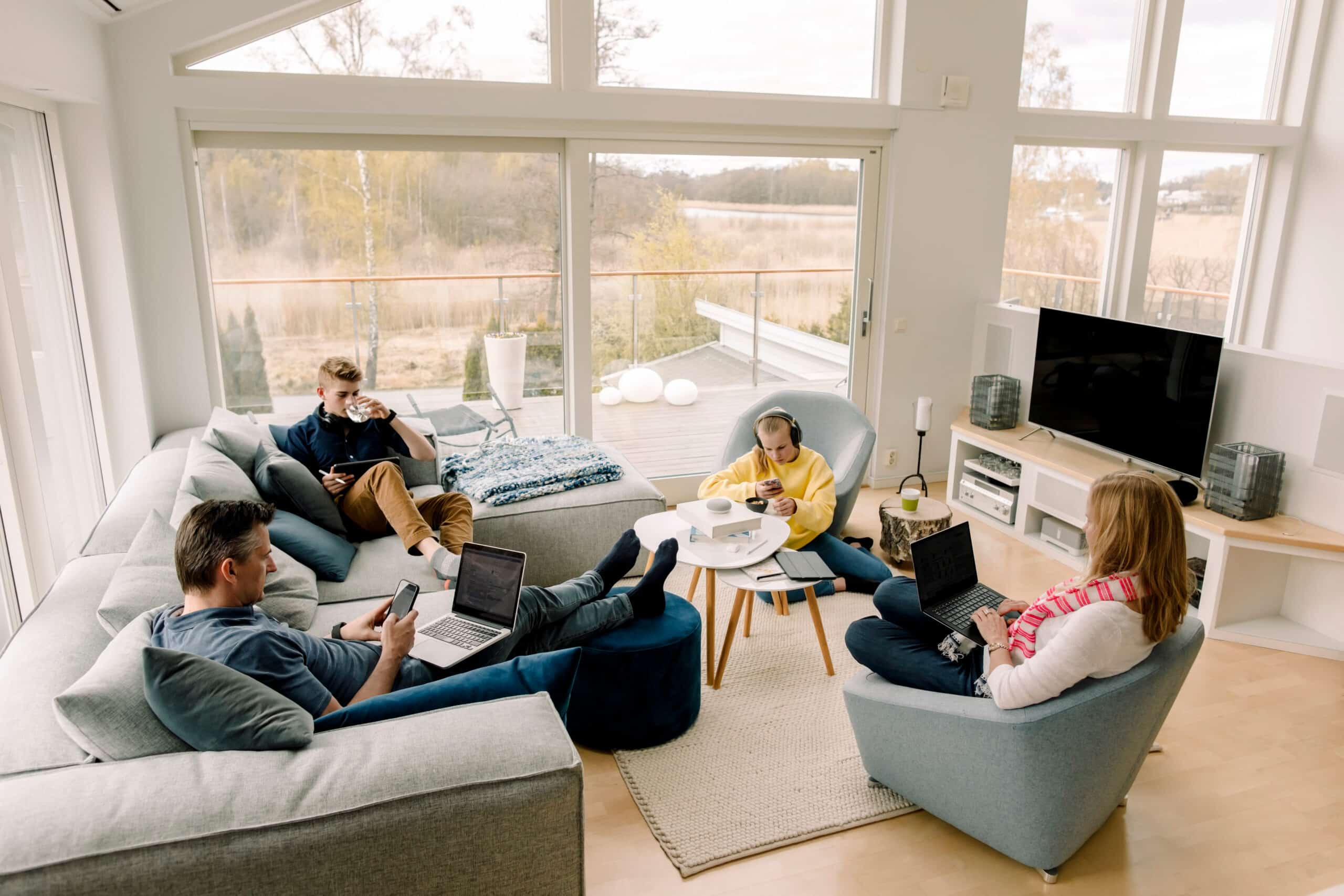 Familie nutzt modernes Homeoffice mit Glasfaserinternet für Arbeiten und Freizeit in einem hellen Wohnzimmer.
