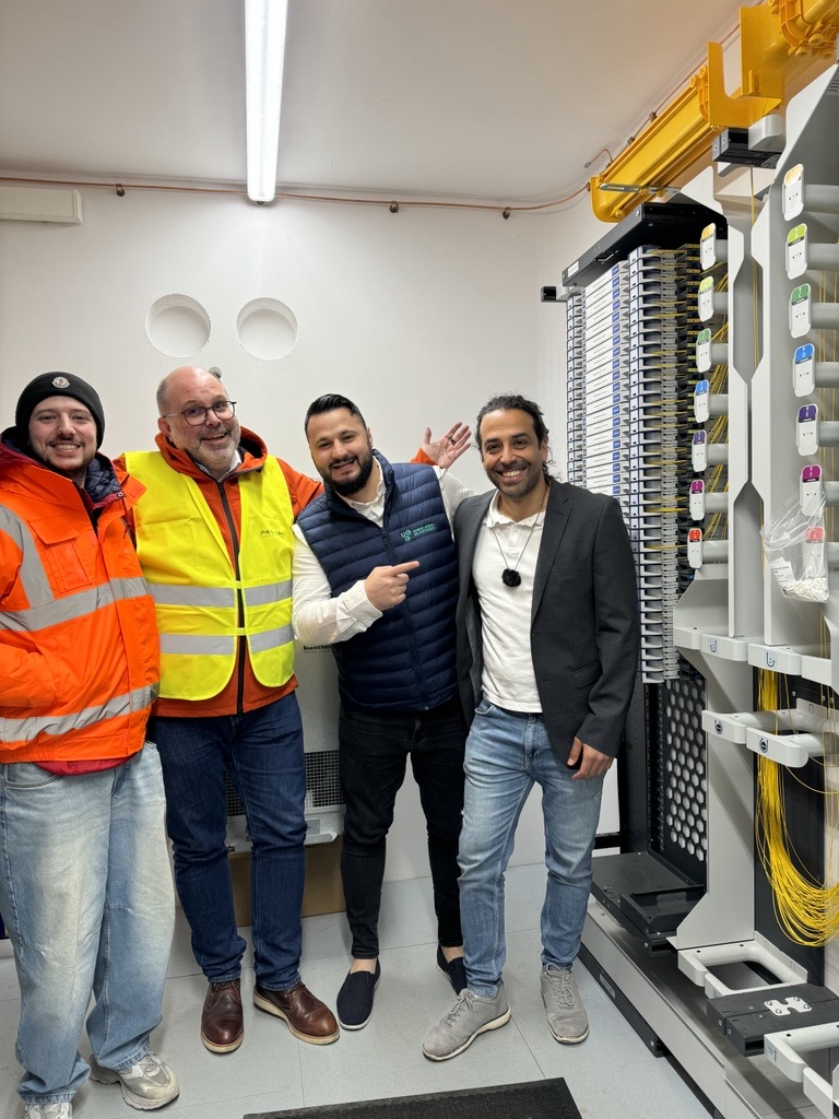 Mitarbeiter von Unsere Grüne Glasfaser präsentieren stolz ihre Infrastruktur in einem modernen Technikraum.